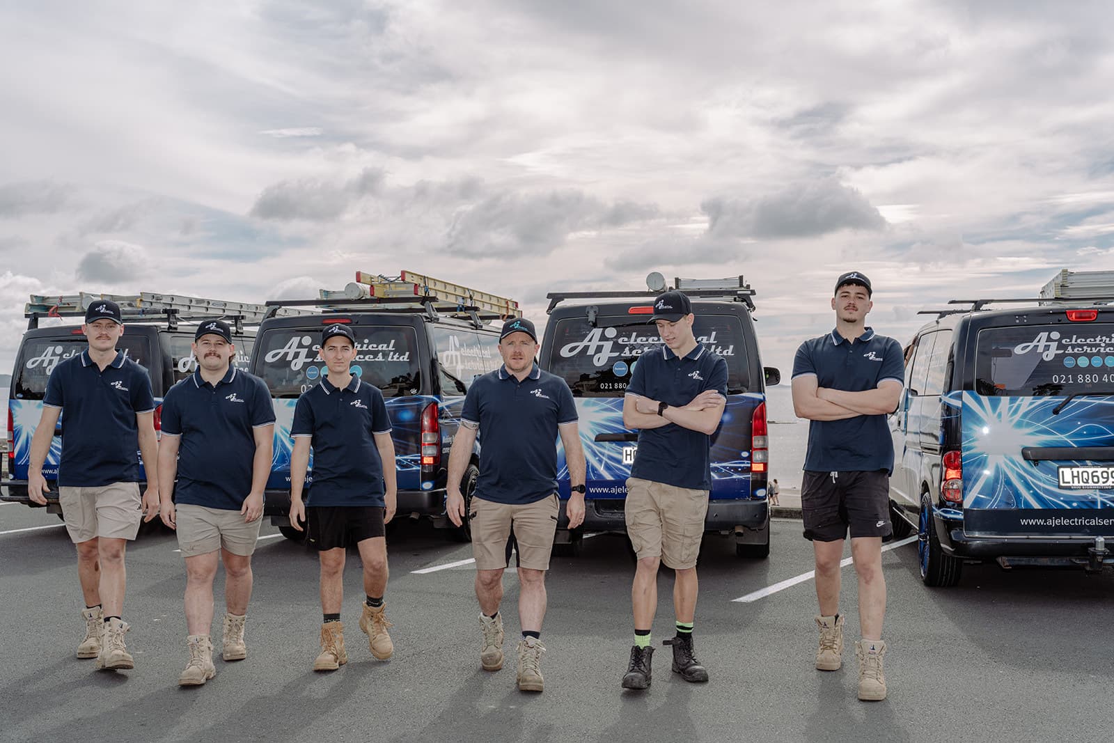 The AJ Electrical team walking towards the camera in front of their vans